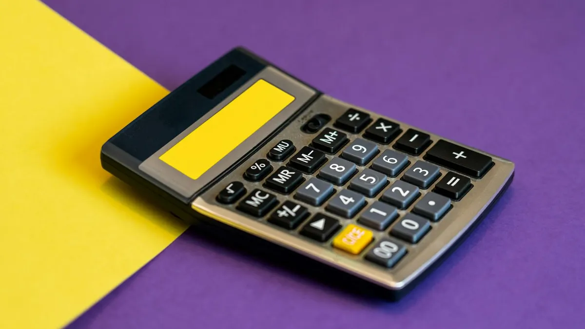 A calculator on vibrant yellow and purple background representing business finance.