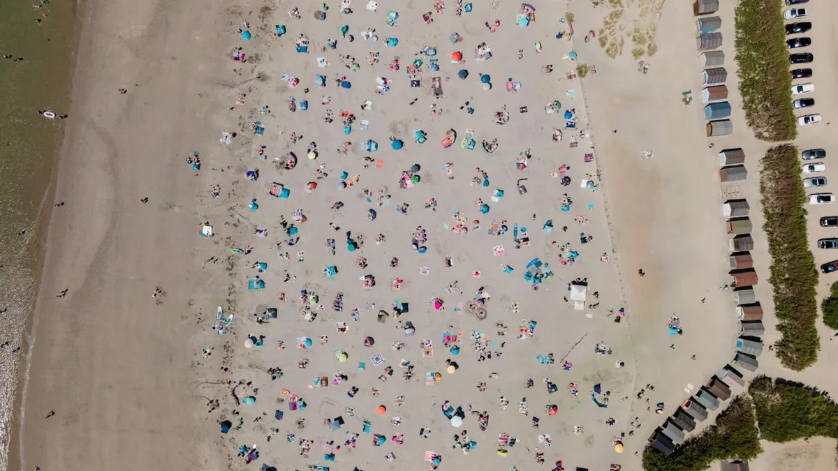 A bird's eye view of West Wittering beach in England, bustling with people on a sunny day.