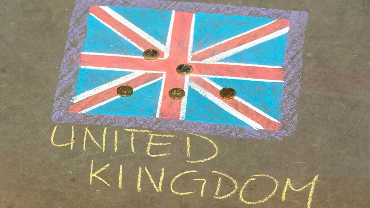 Colorful chalk drawing of the UK flag with coins on pavement, signifying currency and culture.