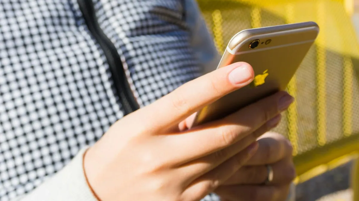 Close-up of a young adult using a smartphone outdoors, highlighting modern technology and connectivity.