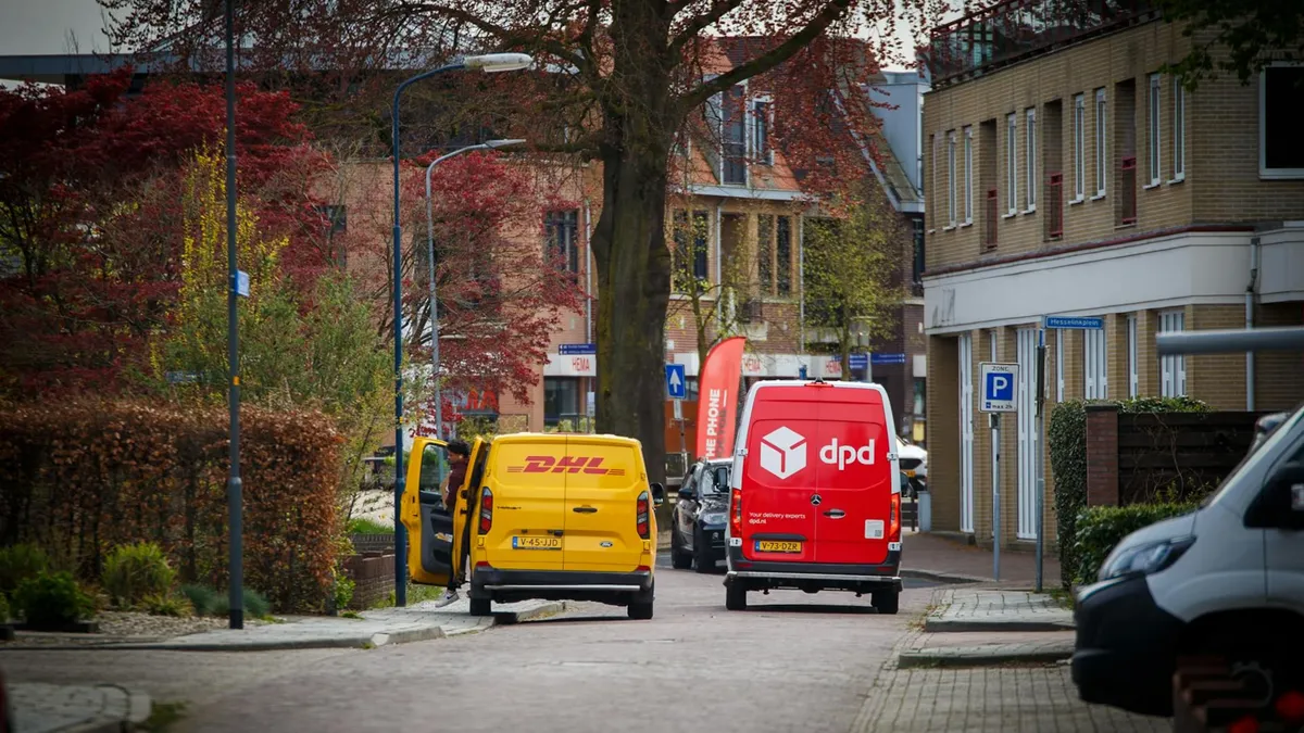DHL and DPD delivery vans parked on a quiet residential street in a Dutch town during the day.