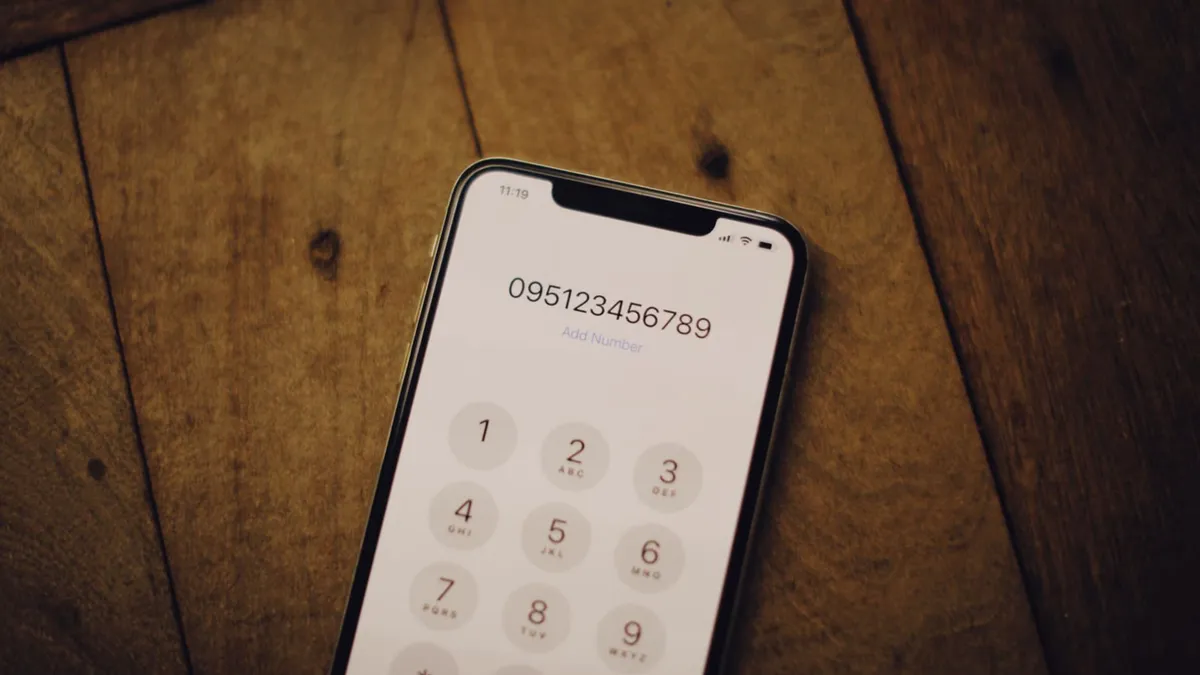 Close-up of a smartphone with a numeric dial pad placed on a wooden surface.