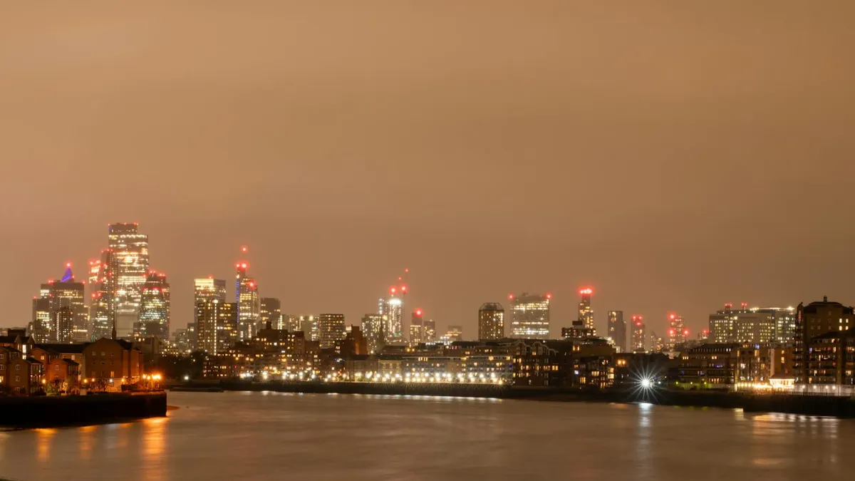 Stunning night view of London's skyline with the River Thames in the foreground, showcasing the city's illuminated towers.