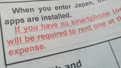 Closeup of a smartphone screen displaying a warning message, representing mobile phone scams and fraudulent activity.