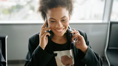 A cheerful call center agent talking on the phone with a headset.