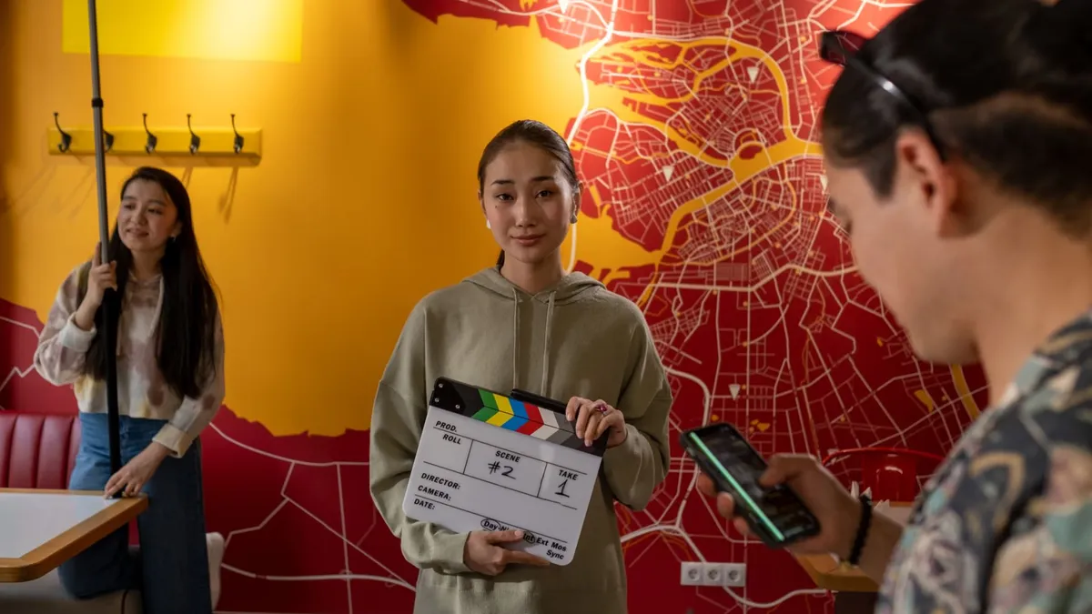 Young film crew in a vibrant indoor setting preparing for a shoot with a clapperboard, set against a city map backdrop.